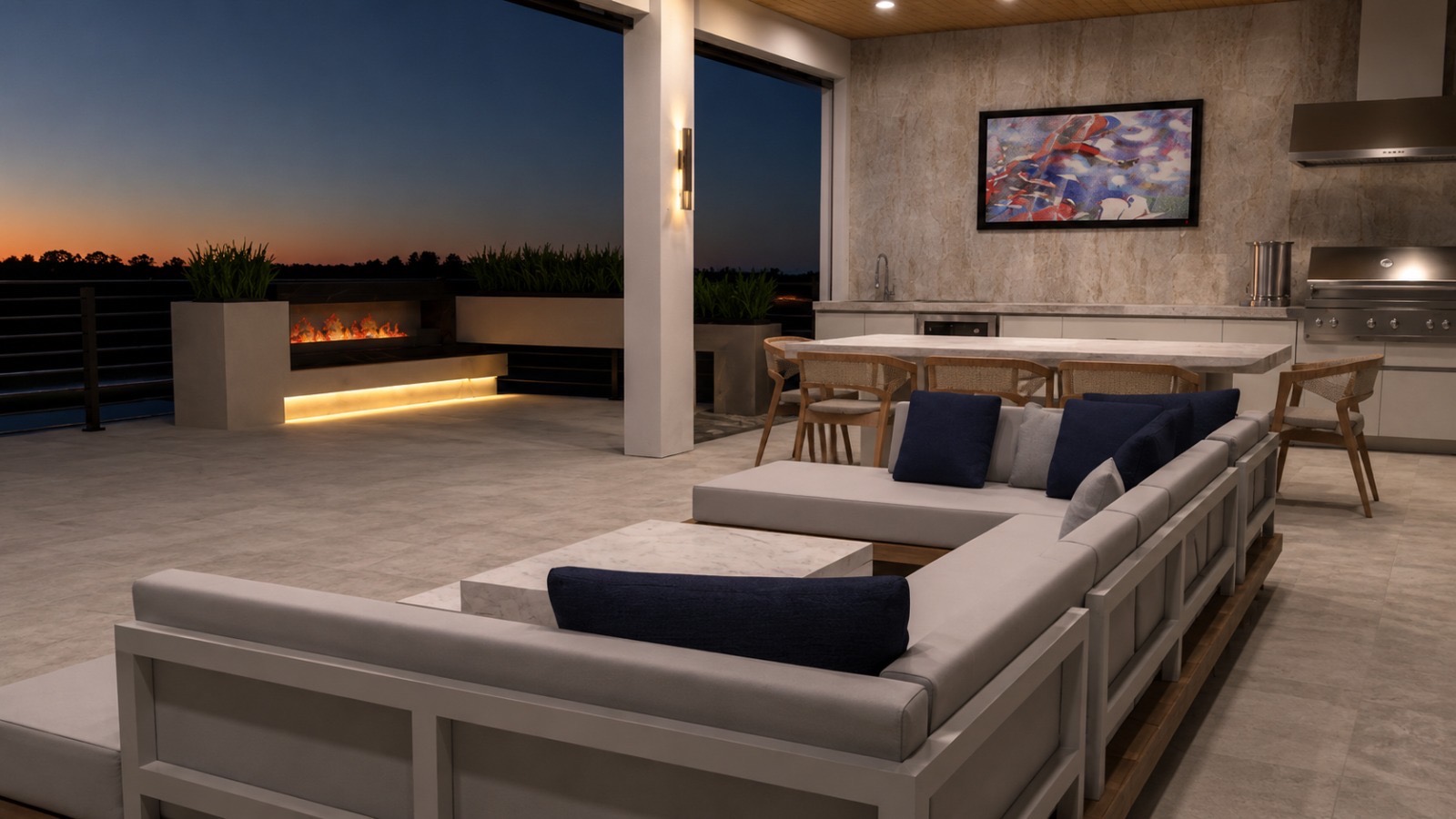 Luxury outdoor living area at dusk with fireplace, built-in kitchen and lounge seating